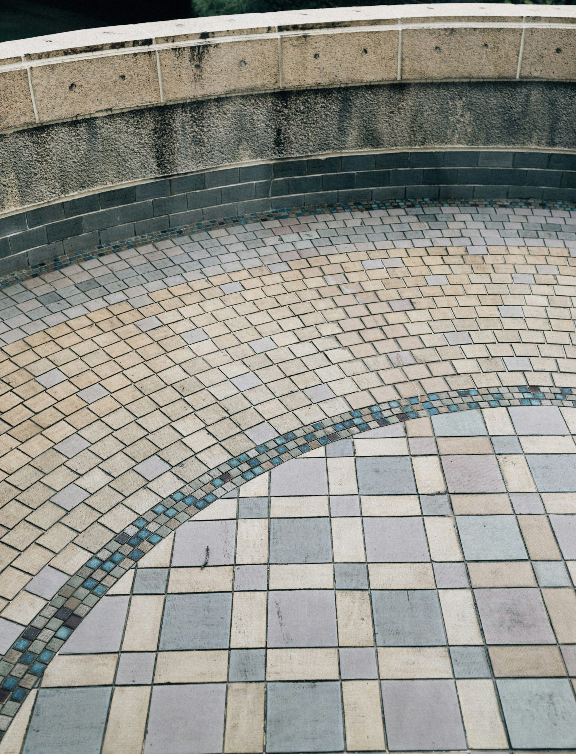 Curved tiled pathway with stone wall and greenery